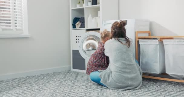 La mujer pasa tiempo con un niño pequeño en el cuarto de lavado, baño, realiza tareas domésticas en licencia de maternidad, cuida de su hija, la niña ayuda a poner la ropa dentro del tambor — Vídeos de Stock