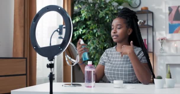 Vrouw registreert huidverzorging tutorial met behulp van telefoon en ring licht. Influencer presenteert cosmetica van het merk waarmee ze samenwerkt. Toning gezicht met verstuiver toner. Aanpassen van de PH van het gezicht — Stockvideo