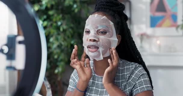 Influencer záznamy krásy tutorial aplikuje list masky na obličej používá kroužek světlo s telefonem, blogger mluví o péči o pleť masáže obličeje s prsty — Stock video
