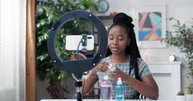 Nüfuzlu blogcu cilt bakımı hakkında konuşuyor. Kadın, yüz yüze nemlendirici sürerken video blogunu telefonla kaydediyor. Bir kız güzellik tedavilerinden bahseder.