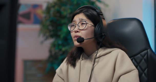 Professionele speler in headset spelen op de computer verloor een ronde in het spel, gebroken hart, teleurgesteld, vrouw dekt gezicht met haar handen, de kamer is verlicht met neon led-verlichting — Stockvideo