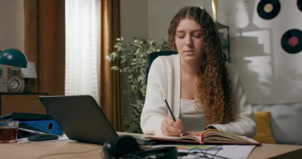Mädchen Mit Lockigem Haar Sitzt Schreibtisch Wohnzimmer Und Macht Sich — Stockvideo
