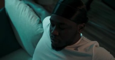 Siyah bandana takan adam kanepede dinleniyor ve başı arkaya eğik. Kirli sakallı adamlar olumsuz duygular yaşıyor. Çöküş, üzücü bir gün, karanlık bir gece feneri ışığı..