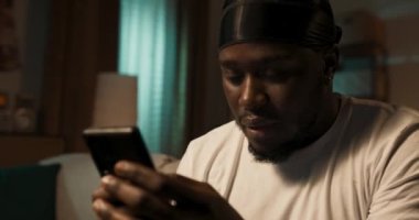 Üzgün genç çocuk, öğrenci akşamları kanepede telefonuyla dinleniyor, elinde akıllı telefon var. Adam kanepeye oturur ve arkadaşlarına mesaj yollar, sosyal medyaya göz atar, kız arkadaşıyla tatsız sohbetler yapar..