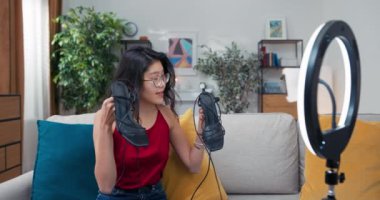 Moda blogcusu kadın kanepeye oturmuş kameranın önünde topuklu ayakkabılarını gösteriyor. Kanal için vlog bölümü çekerken modaya uygun ayakkabıları gösteren etkili stilist.