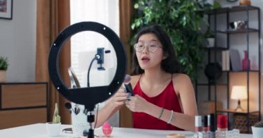 Bir acemi, halka ışığı ve telefon yardımıyla sosyal medyada bir video çeker. Popüler makyaj sanatçısı vakıf için favori fırçalarını, bronzlaştırıcıyı, kız tüylerini gösteriyor..