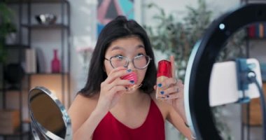 Güzellik modeli makyaj yapıyor. Kız aynaya bakıyor ve temelini pembe süngerle kuruyor. Güzel genç kadın sosyal medyada izleyicilere özel ipuçları kaydediyor..