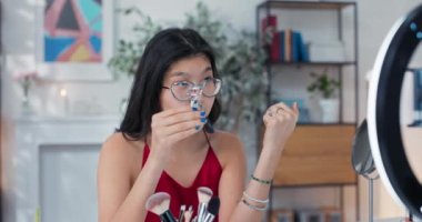 Güzellik blogcusu, kamera karşısında kirpik kıvırıcısını gösteriyor. Bir kız makyaj aksesuarlarını nasıl düzgün kullanacağını açıklar. Etkilenen kişi güzel kirpiklerin sırrını açığa çıkarır..