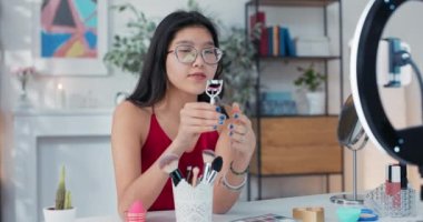 Güzellik blogcusu, kamera karşısında kirpik kıvırıcısını gösteriyor. Bir kız makyaj aksesuarlarını nasıl düzgün kullanacağını açıklar. Etkilenen kişi güzel kirpiklerin sırrını açığa çıkarır..