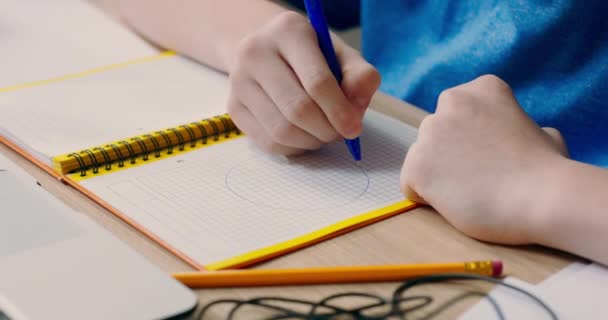 円を描く若い男の子の手のショット ノートブックの紙の上の図 子供は学校のためのノートを作成し 学びます — ストック動画