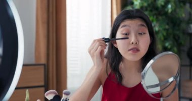 Influencer, sosyal medya üzerinden çalıştığı markanın ürün değerlendirmelerini kaydediyor. Makyaj dersi, kirpiklerin nasıl boyanacağı üzerine yazılar. Bir kadın kozmetik ürünlerini açar ve kirpiklerinde rimel kullanır..