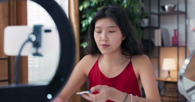 Makyaj malzemesi. Beyaz bir pamukla yüzünü temizleyen bir kadın aynada kendine bakıyor. Sosyal medya kanalı için halkalı telefon kullanarak güzellik dersi vlog 'u kaydeden nüfuzlu kişi.