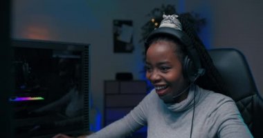 Siyah tenli, Afro-Amerikan güzelliğinde bir kızla konuşmak için kulaklıklı, genç ve güzel bir bayan oyuncu gecenin karanlığında ışıklarla aydınlanıyor..