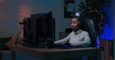 Gelişmiş bayan oyuncular bilgisayar başında kulaklıkla konuştuğu takımla oynuyor, sanal çevrimiçi şampiyonluğu kazanıyor, kız zafere sevinçle el kaldırıyor..