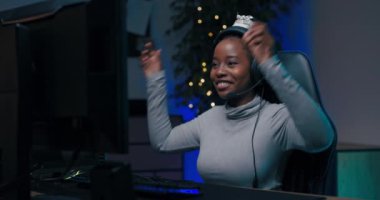 Profesyonel bir oyuncunun kazandığı oyun sayesinde zafer dansı. Kadın, takım arkadaşlarıyla kulaklıkla konuşmaktan keyif alıyor. Sevinçten gülümsüyor. Karanlık oda ışığı getirdi.