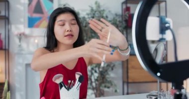 Güzellik Etkilendirici, telefon zili ile video bloğu kaydediyor. Kız göz makyajı fırçasından bahsediyor. Asyalı güzellik yarışmacısı canlı olarak sunar.