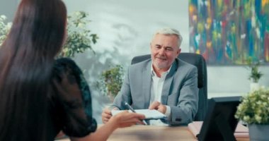 Şirkette sekreterlikten patronluğa adaylığını koyan kişi iş görüşmesinde, genç kız süresiz sözleşme imzalıyor, müdüre imzalaması için belge veriyor, el sıkışma işbirliği yapıyor, tebrikler.