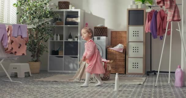 穿着粉色连衣裙的可爱小女孩在家里的浴室中央跳舞 洗衣房周围放着肥皂盒 在孩子们身边嬉戏 — 图库视频影像