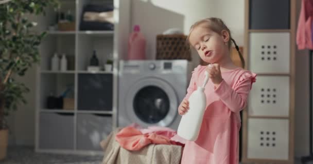 一双大眼睛 可爱的小宝宝 穿着粉红色的衣服 女孩在洗衣房里用液体 帮妈妈做家务活 女演员 影响者推荐产品 — 图库视频影像