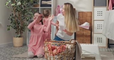 Pembe elbiseli ve örgülü küçük bir kız elinde hasır bir sepetle annesinin yanında oturur ve odadaki radyodan gelen müzikle dans eder..
