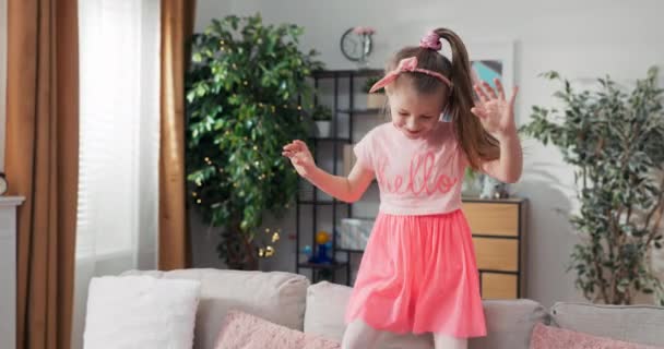 Happy Little Girl Plays Alone Sofa Living Room Jumps Sofa — Vídeo de Stock