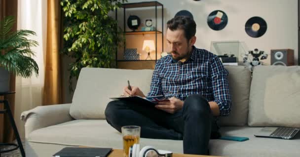 Άνθρωπος Κάθεται Στον Καναπέ Στο Σπίτι Κάνοντας Μαθήματά Του Για — Αρχείο Βίντεο