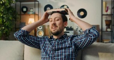A man trying to study for an English exam attends classes at an adult school. He is bored with studying, puts a book on head, reaches for phone and gets distracted