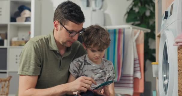 Pai Mostra Filho Como Operar Máquina Lavar Partir Aplicativo Móvel — Vídeo de Stock