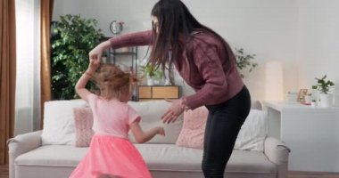 Neşeli anne ev hareketli en sevdiğiniz şarkıda birlikte dans, oturma odasında duran küçük kızı. Çocuk sahibi eğlenceli ablası ile dadı ya da sevgi dolu anne aktif eğlence ve yaşam tarzı kavramı.