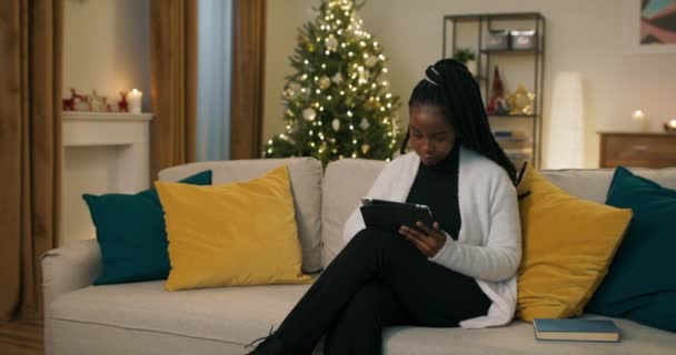 African Looking Student Sits Sofa Holding Tablet Ordering Christmas Presents — Stock videók