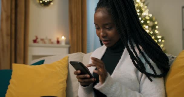 소파에 전화기를 아프리카의 매력적 크리스마스 장식을 장식을 합니다 — 비디오