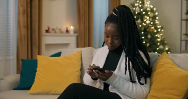 Afroamerykanin Ubrany Czarne Ubrania Biały Sweter Siedzący Kanapie Trzymający Telefon — Wideo stockowe