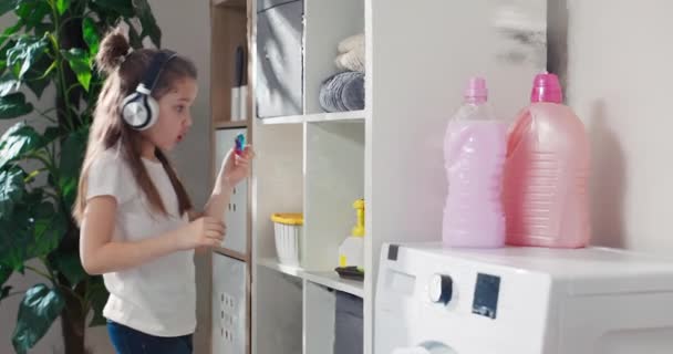 Little Girl Wearing Headphones Listening Music Enters Laundry Room Takes — Stockvideo