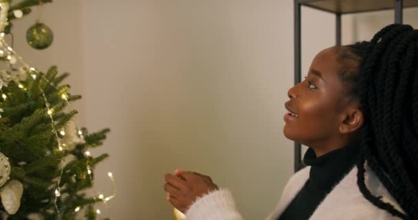 Afrykański Student Ozdabia Choinkę Świecącymi Girlandami Dziewczyna Trzyma Dekorację Kształcie — Wideo stockowe