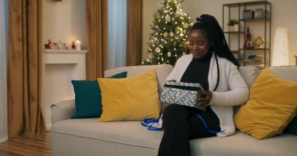 Beautiful Student African Appearance Sits Couch Unpacks Christmas Present Girl — Stockvideo