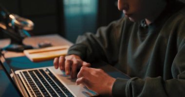 Ödev yapan genç çocuk bilgisayarla odada tek başına oturuyor. Ergen laptop 'da video izliyor ve internette geziniyor..