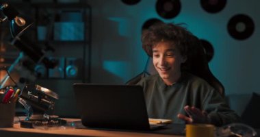 Genç bir çocuk bir arkadaşıyla dizüstü bilgisayardan konuşuyor. O, selam vermek için arkadaşına el sallar. Robotlara olan ortak ilgilerini tartışıyorlar..