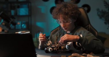 Güvenlik gözlüğü takan bir çocuğun portresi robot lehimliyor, çocuk yeni yetenekler geliştiriyor, lehim kabloları, elektrik kabloları, tamir hasarı....