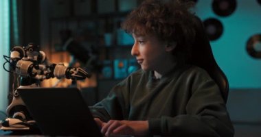 Yetenekli genç çocuk karanlıkta bir odada oturuyor ve bir robotu dizüstü bilgisayara programlıyor, yeni özellikler ekliyor, beşlik çakıyor, robot teknolojisine ilgi duyuyor..