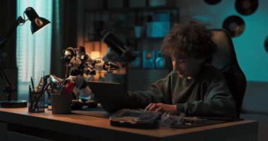 Yetenekli genç çocuk karanlıkta bir odada oturuyor ve bir robotu dizüstü bilgisayara programlıyor, yeni özellikler ekliyor, beşlik çakıyor, robot teknolojisine ilgi duyuyor..