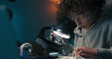 Masada güvenlik gözlüğü takan Afro çocuk anakart lehimliyor. Çocuk elektronik için bir hobi geliştiriyor ve bir okul projesi üzerinde çalışıyor..