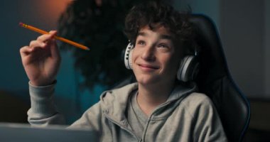 Genç bir çocuk masasında karanlık bir odada oturuyor, yaratıcılığa kendini kaptırıyor, kablosuz kulaklıkla müzik dinliyor, kalemi kafasına yaklaştırıyor, yoğun bir şekilde bir fikir arıyor..