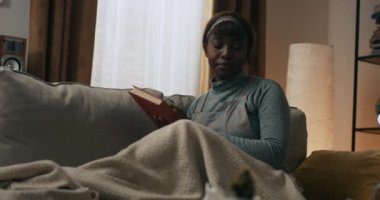 A woman looks through the pages of a book, curious about the next pages. She looks with interest at the successive pages of the novel. The woman is reading the book.