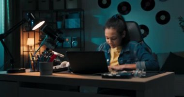 Kız dizüstü bilgisayarın önünde özenle çalışıyor, defterinde kalem olan notlar, yeniden yazıyor, e-kitap okuyor, uzaktan eğitim alıyor, sınava hazırlanıyor, uzaktan ders veriyor..