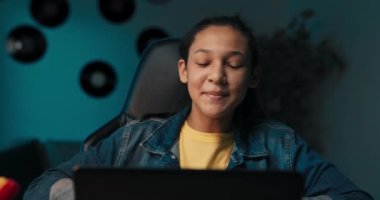 Close-up of girls hands taking notes with pencil in notebook, laptop, headphones, teenage girl has remote lessons, distance learning, online school.
