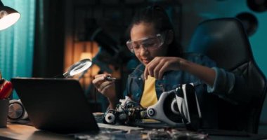 Close-up soldering, young teenager fixes cables,robot wires, small smoke rises from heated electronics, child spends leisure time on hobby.