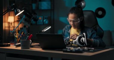 Close-up soldering, young teenager fixes cables,robot wires, small smoke rises from heated electronics, child spends leisure time on hobby.