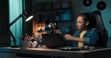 Portrait of a girl wearing safety glasses engaged in soldering a robot, child develops new skills, solders cables, electrical wires, repairs damage.