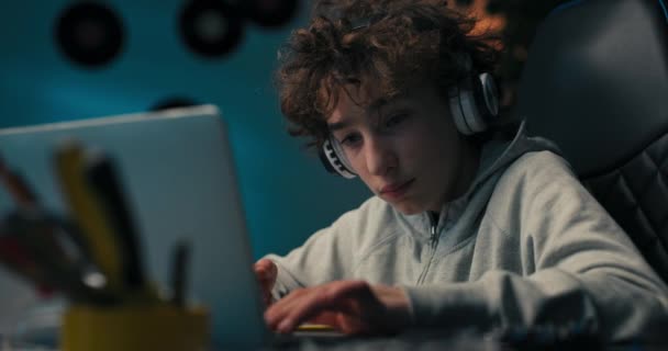 Young Boy Sits His Desk Wireless Headphones Front Computer Taking — Vídeo de Stock
