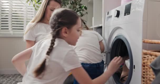 妇女在洗衣房 浴室与幼儿呆在一起 在产假期间做家务 照顾女儿 教女孩如何操作洗衣机 — 图库视频影像